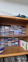 Wooden shelving with stacks of jewel-case CDs and cassettes