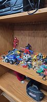 Shelf with multiple loose toys including blue monster truck and figures