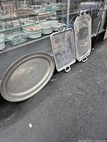 Group view of oval platter and two rectangular trays leaning against display case