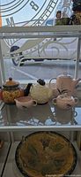 All three teapots plus matching sugar bowl and creamer on glass shelf