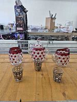 Group shot of ruby flash sugar bowl, creamer, three metal-overlay shot glasses