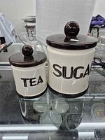Front view of both ceramic canisters showing labels and lids