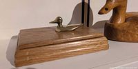 Oak box with brass duck knob beside carved wood duck decoy