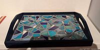 Top view of rectangular wood tray with blue mosaic tile surface