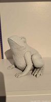Front view of light grey seated frog figurine