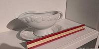 Side view of gravy boat on underplate next to ruler