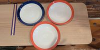 Three large shallow bowls with blue or orange rims