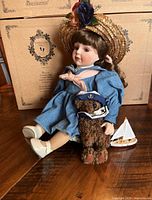 Full doll seated with bear and sailboat, box in background