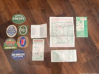 All items laid out: six coasters, scorecard, brochures, maps