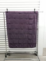 Full view of purple weighted blanket hanging, showing size and quilted grid