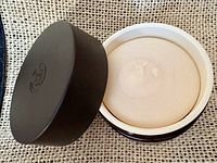 Open jar showing beige scrub and black lid