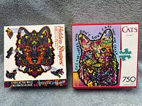 Front view of Hidden Shapes 300-piece and Cats 750-piece puzzle boxes