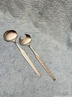 Both utensils showing hammered handles on grey background