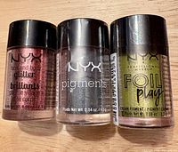 Front view of three sealed NYX eye colour vials showing labels and shades