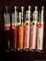 Front view of six Wet n Wild lip gloss tubes showing colours and seals