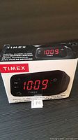 Front of sealed Timex digital alarm clock box showing red LED display and battery backup feature