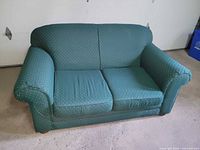 front view of green dotted loveseat showing seat cushions, arms and wood feet