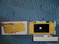 Box opened showing yellow Nintendo Switch Lite with screen protector and cardboard insert