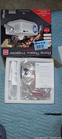 Box top showing RCA Home Theater Projector branding and accessory icons