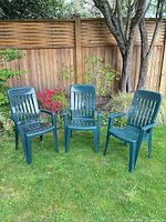 Front view of the three matching green plastic armchairs on lawn