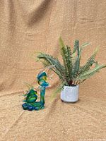 Glass fish sculpture beside faux fern planter
