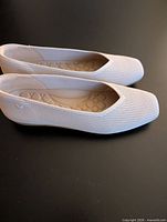 Side profile of both flats showing knit texture and color