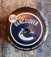 Front of puck-shaped package showing Vancouver Canucks logo and size sticker