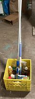 Crate holding cleaning products, two telescopic tools visible