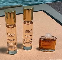 Three perfume bottles: two Chanel Coco Mademoiselle refills with caps, one YSL Opium miniature