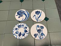 Set of four coasters shown top view displaying individual blue tulip designs