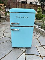 Front view of turquoise Galanz mini fridge with two chrome handles