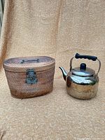 Stainless kettle beside wicker tea caddy