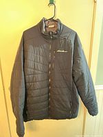 Front view quilted charcoal side showing logo and pockets