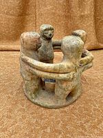 Side view of pottery candle holder showing four figures clasping arms
