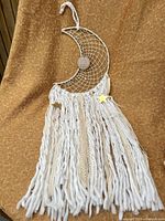 Full view of crescent moon wall hanging against fabric background