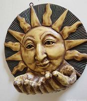 Front view of sun face plaque with cupped hands