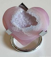 Heart-shaped pink quartz geode in metal stand showing druzy center