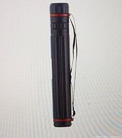 Full view of poster tube showing ribbed body, red rings, strap