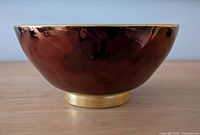 Side view of red Carlton Ware bowl showing glaze and gold rim
