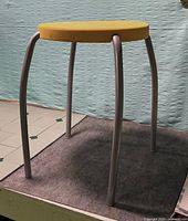 Full view of stool showing yellow seat and metal legs