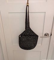 Full view of Le Sak black and white shoulder bag hanging to show overall shape and strap length