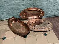 All three silver plated items: two trays and trivet