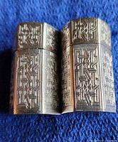 Two shakers joined together showing overall engraved pattern