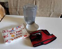 All three items together: food dispenser, harness, folded tea towel