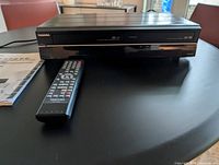 Front view of Toshiba DVR630 with remote and manual visible