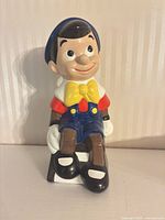 Front view of Pinocchio figurine showing full colour and seated pose