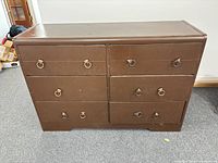 Front view of brown six-drawer dresser with ring pulls