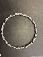 Full view of the twisted rope bangle bracelet lying flat