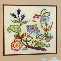 Full view of framed crewel embroidery under glass