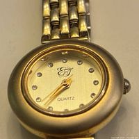 Dial and bracelet close-up showing EG logo, crystal hour markers, gold-tone finish